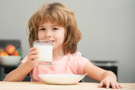 Photo for Cute little child with glass of milk at table in kitchen. Kid eating breakfast. Child eating healthy food. Organic milk with calcium. Small child enjoy delicious nutritious lactose free yoghurt - Royalty Free Image