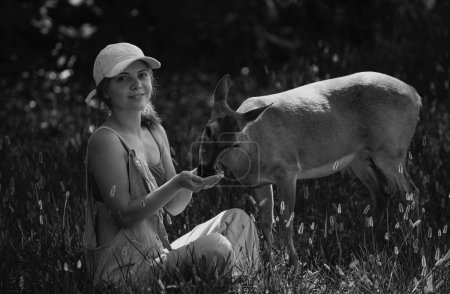 Foto de Unidad con la naturaleza. Chica alimenta ciervos. Protección del medio ambiente. A los animales les importa. Mujer alimentando a Fawn. Parque de animales - Imagen libre de derechos