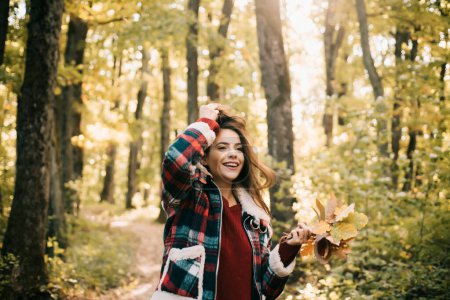 Foto de Feliz joven en el parque en el soleado día de otoño. Árboles amarillos y hojas. Chica hermosa alegre en suéter rojo al aire libre en hermoso día de otoño. Hola Otoño - Imagen libre de derechos