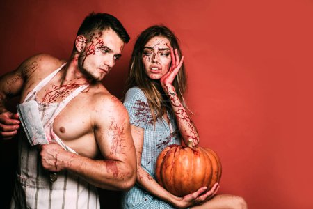 Téléchargez les photos : Halloween fête étudiante dans le sang. Deux hommes musclés et une jeune femme ensanglantée avec des blessures et du sang rouge. Terrifiant couple zombie - en image libre de droit