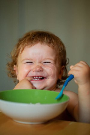 Foto de Bebé sonriente comiendo comida. Lanzamiento de niño con cuchara - Imagen libre de derechos
