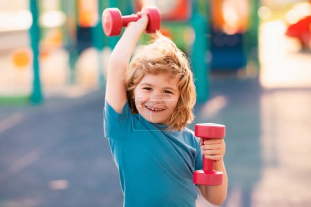 Photo for Kids sport training on playground outdoor. Child workout. Kid sport. Child exercising with dumbbells. Sporty child with dumbbell - Royalty Free Image