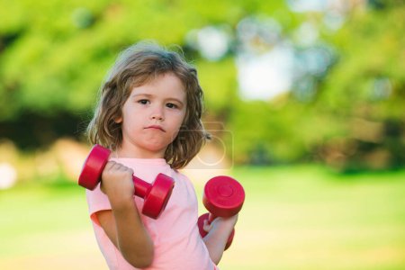 Photo for Fitness dumbbells kid exercise workout outdoor. Boy sporty child with dumbbells. Sport portrait kids - Royalty Free Image