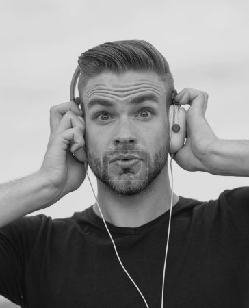 Photo for Excited Man listening music in headphones. Emotional surprised portrait guy. Young bearded casual man with and earphones - Royalty Free Image