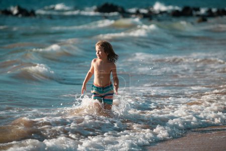 Foto de Niño en la costa. Un niño jugando en el océano. Vacaciones en el mar. El niño en olas - Imagen libre de derechos