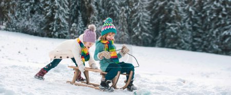 Photo for Funny children in snow ride on sled. Winter outdoors games. Happy Christmas family vacation concept. Kids enjoy the holiday - Royalty Free Image