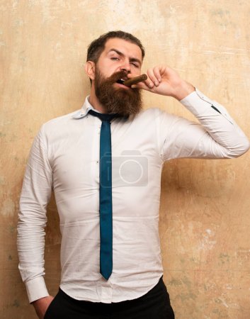 Téléchargez les photos : Portrait d'un bel homme barbu fumant un cigare - en image libre de droit