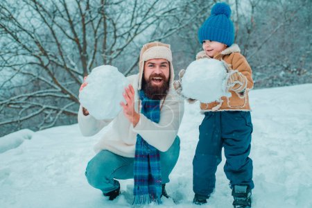 Heureux père et fils jouent pendant la période hivernale de Noël. Bonne famille souriante le jour ensoleillé d'hiver. Concept de famille amicale

