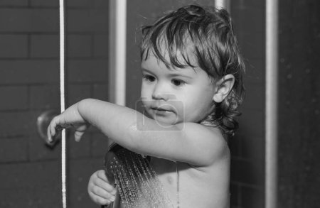 Téléchargez les photos : Mignon enfant se lave le corps dans le bain. Bains de bébé heureux drôles dans la baignoire avec de l'eau et de la mousse. Hygiène des enfants - en image libre de droit