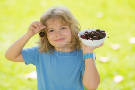 Foto de Cara de niño de verano. Niño niño sostenga las cerezas plato en el parque. Cereza para niños - Imagen libre de derechos