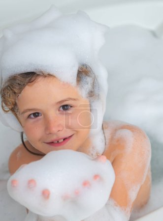 Foto de Champú para niños. Espuma en la cabeza del niño. Niño en un baño con espuma. Procedimientos de baño e higiene infantil - Imagen libre de derechos