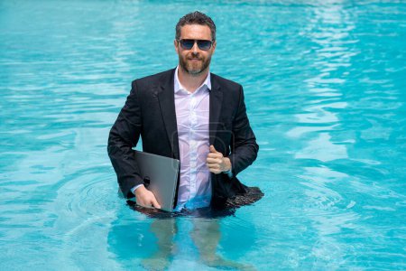 Photo for Summer weekend and remote freelance work. Crazy comic business. Funny businessman in suit with laptop in summer swimming pool water. Remote summer work. Businessman relaxing in a pool in a suit - Royalty Free Image