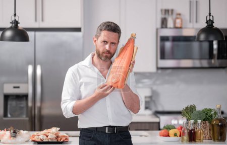 Photo for Man in modern kitchen preparing fish salmon. Handsome man is cooking fresh fish salmon seafood crab and shrimp and lobster in the kitchen at home - Royalty Free Image