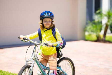 Foto de Un niño pequeño monta en bicicleta en el parque. Chico en bicicleta. Feliz niño sonriente en casco montando una bicicleta. El chico empieza a andar en bicicleta. Deportiva bicicleta de niño montar en bicicleta. Bicicleta infantil - Imagen libre de derechos