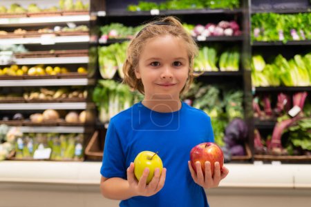 Foto de Niño con frutas de manzana en el supermercado. Pequeño niño eligiendo comida en la tienda de comestibles o en un supermercado - Imagen libre de derechos