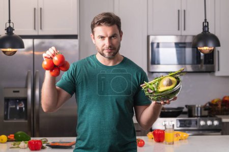 Photo for Middle aged man cooking in kitchen. Man on kitchen with vegetables. Portrait of casual man cooking in the kitchen with vegetable ingredients. Guy preparing salad at home in kitchen - Royalty Free Image