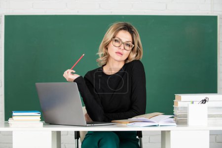 Photo for Portrait of beautiful teacher or female tutor working at table in college or high school. Young women student studying in class - Royalty Free Image