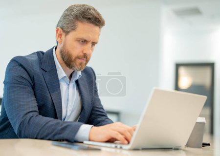 Photo for Man with laptop at office. Business man in suit in office work on laptop computer. Office worker using laptop. Business man work on laptop. Businessman have online work in modern office interior - Royalty Free Image