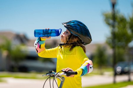 Photo for Kid riding bike in a helmet. Child riding bike in protective helmet. Safety kids sports and activity. Happy kid boy riding bike in summer park. Bike helmet, bicycle safety, cycling accessories - Royalty Free Image