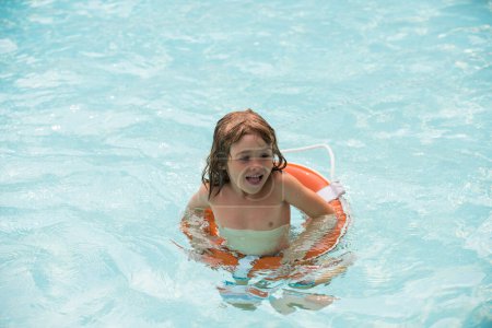 Téléchargez les photos : Enfant nageant dans la piscine. Vacances d'été. Le garçon s'amuse à Aquapark. Joyeux enfant avec bouée de sauvetage. Enfant d'été - en image libre de droit