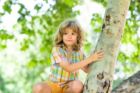 Téléchargez les photos : Kid climbing on a tree branch outdoor - en image libre de droit