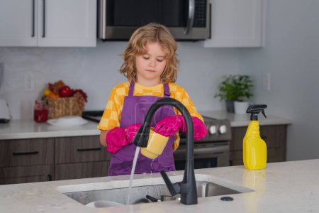Foto de Kid limpieza de kithen ayudar con las tareas domésticas. Lindo niño limpieza, casa limpia del niño - Imagen libre de derechos