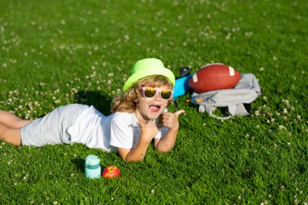 Téléchargez les photos : Child having fun outside. Happy children rest fun outdoors. Kids relaxing in spring park. Boy lying on green grass - en image libre de droit