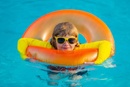 Photo for Swimming, summer vacation. Child swim in pool on inflatable ring. Kid with inflatable ring in swimming pool. Summer vacation. Child in swiming pool. Kid floating in sea water - Royalty Free Image