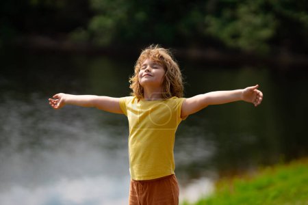 Photo for Happy kid with arms up enjoying freedom in nature. Kid enjoying freedom raising arms up. Funny happy little boy having fun at the park. Kid enjoy summer, childhood. Kid in nature - Royalty Free Image