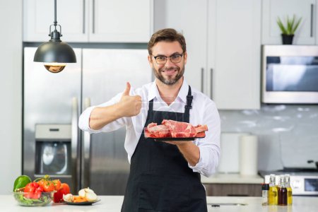 Photo for Chef cooking raw meat fillet in the kitchen. Restaurant menu concept. Male portrait of chef man hold meat in the kitchen. Raw meat fillet for advertising - Royalty Free Image