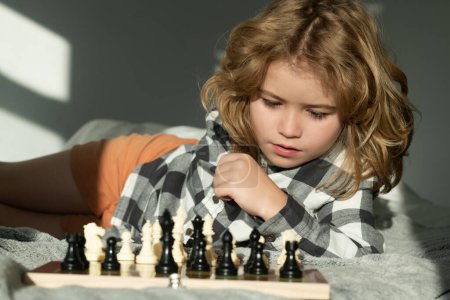 Photo for Cute child playing chess at home. Clever concentrated and thinking kid playing chess. Kids brain development and logic game - Royalty Free Image
