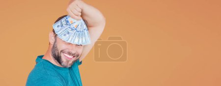 Téléchargez les photos : Un homme d'âge moyen tenant des billets en dollars. Bonne chance, bannière. Concept d'argent comptant en dollars. Réjouit de gagner de l'argent. Homme détiennent de l'argent liquide - en image libre de droit