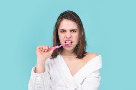 Téléchargez les photos : Jeune femme drôle brossant les dents avec une brosse à dents pendant les procédures d'hygiène du matin fond isolé, portrai facial - en image libre de droit