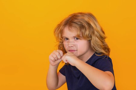 Photo for Angry child with fist gesture fight, hit on yellow studio isolated background. Kid boy with mad expression handed punch. Bad kids behavior. Fury boy - Royalty Free Image