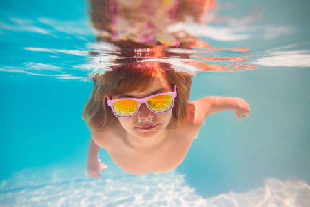 Photo for Child dives into the water in swimming pool. little kid swim underwater in pool. Child swimming underwater in sea or pool water. Summer vacation fun. Underwater portrait cute kid in swimming pool - Royalty Free Image