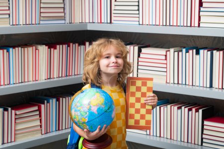 Téléchargez les photos : Écolier avec globe mondial et échecs, enfance. Un écolier de 7-8 ans avec un livre retourne à l'école. Petite étudiante. Concept d'éducation - en image libre de droit