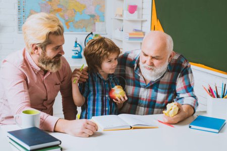 Photo for Grandfather father and son learning to write and read, men generation. Three different generations ages grandfather father and child son study together in home classroom - Royalty Free Image
