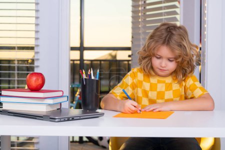 Foto de Child from elementary school writing school homework at home. Little student, clever nerd pupil ready to study. First time to school. Concept of education and learning - Imagen libre de derechos