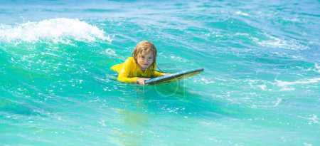 Photo for Kid play in summer sea. Summer vacation with child. Kid girl is learning surfing, riding a wave. Little boy swim on kids surf board, learning surfing - Royalty Free Image