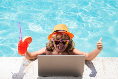 Photo for Excited kid drink summer cocktail and using laptop in swimming pool - Royalty Free Image