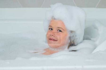 Photo for Kids face in foam. Boy child in a bath with foam. Kids bathing and hygiene procedures - Royalty Free Image