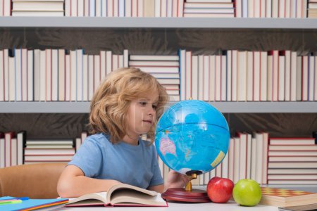 Photo for School pupil looking at globe in library, geography lesson. School child studying in classroom at elementary school. Kid studying on lesson in class at elementary school - Royalty Free Image