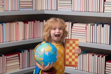 Téléchargez les photos : Écolier avec globe mondial et échecs, enfance. Un gamin de l'école primaire avec un livre. Petite étudiante, intelligente élève nerd prête à étudier. Concept d'éducation et d'apprentissage - en image libre de droit