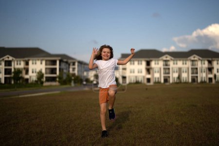 Photo for Child run. Excited kid boy running on grass. Kid boy playing and running in the summer park. Cute kid boy running across american neighborhood street. Summer, childhood, leisure and people concept - Royalty Free Image