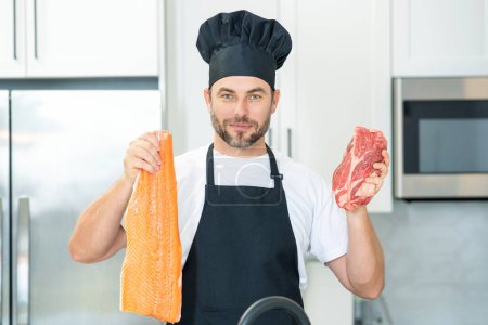 Foto de Salud, concepto de proteína natural. Hombre guapo en la cocina cocinando pescado y carne, salmón y carne de res en la cocina. Concepto de comida saludable. Dieta saludable, proteína de carne - Imagen libre de derechos