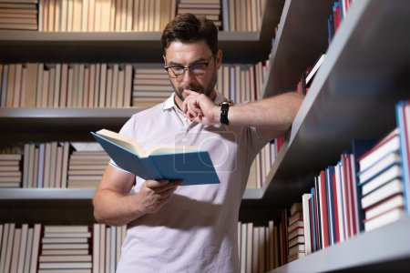 Photo for Portrait of teacher with book in library classroom. Handsome teacher in university library. Teachers Day. Teacher giving classes. School teacher in library. Tutor at college library on bookshelf - Royalty Free Image
