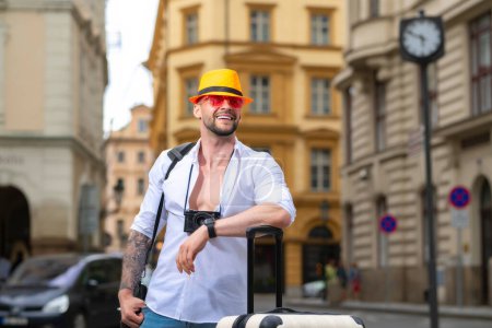 Foto de Viajero, turista de moda. Hombre turista viajero en ropa casual sombrero con maleta. Hombre turista viajero en ropa casual con maleta. Viajar al extranjero los fines de semana. Concepto de viaje - Imagen libre de derechos