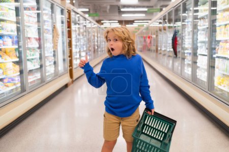 Téléchargez les photos : Enfant avec panier. Enfant achetant des fruits au supermarché. Le petit garçon achète des légumes frais à l'épicerie. Un gamin qui choisit des légumes. Aliments sains - en image libre de droit