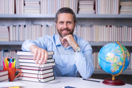 Photo for Teachers day. Teacher in school classroom. Knowledge and education with middle aged teacher. Hispanic teacher with book. Man teaching lesson in class. Teacher from university exam. College teachers - Royalty Free Image