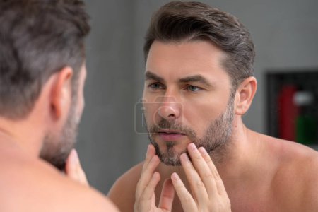 Photo for Close-up portrait of perfect brunet man touching chin and skin. Handsome man touching face in front of the mirror in bath. Perfect skin. Man cosmetic, skin treatment. Hygiene and skin care male face - Royalty Free Image